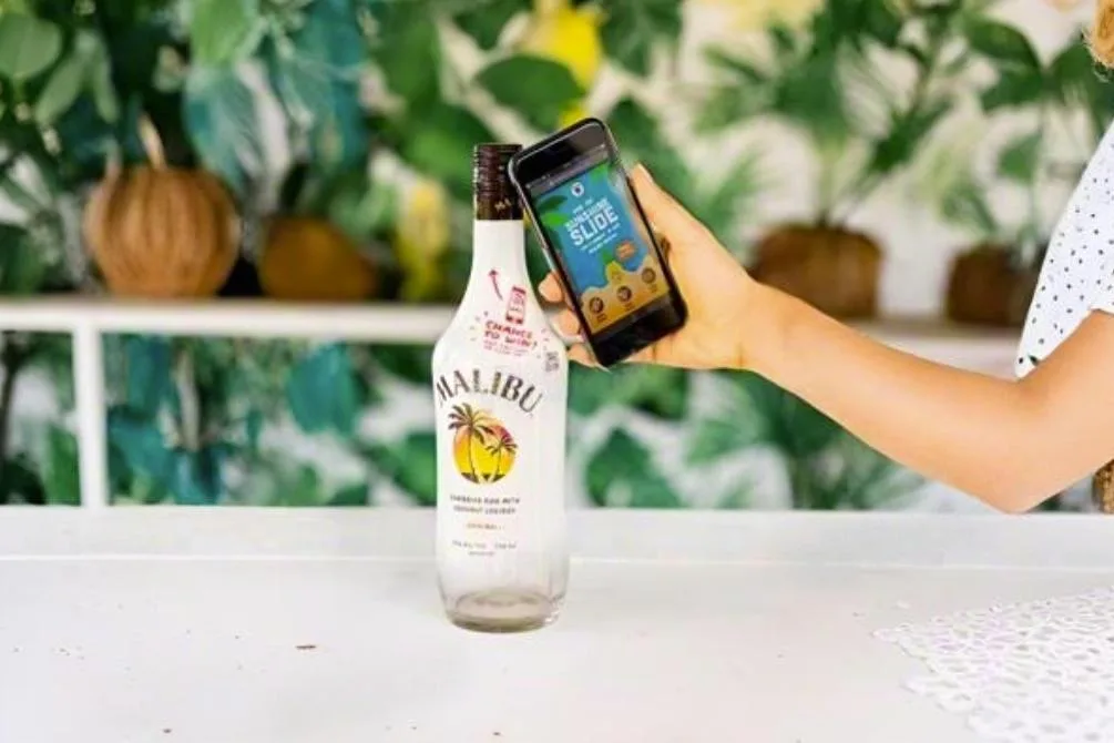 A smartphone held near a sleek glass bottle, showing the NFC connection