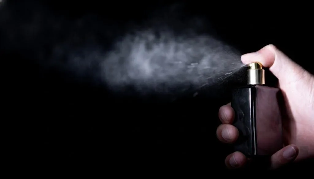 A fine mist sprayer in action, creating a delicate and even cloud of spray from a sleek glass bottle.