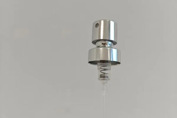 A close-up of a perfume bottle's metal sprayer mechanism