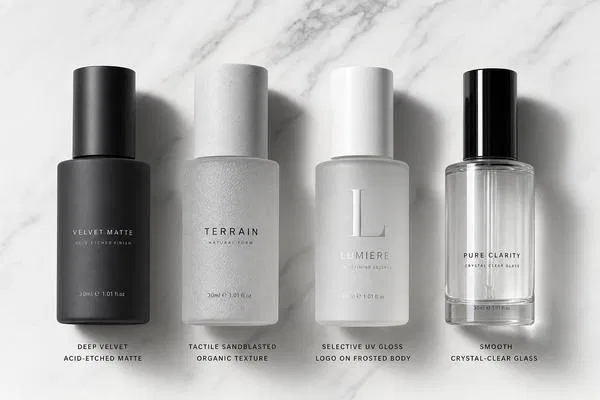 Four premium glass bottle surface treatments comparison: acid-etched velvet matte, sandblasted organic texture, selective UV gloss, and crystal-clear smooth glass