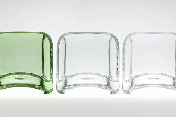 Close-up cross-section of glass bottles showing the difference in color tint between standard, high flint, and super flint glass grades