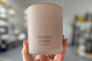 Frosted glass candle jar with a single color screen printed brand name held in hand