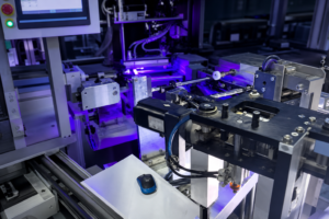 Automated screen printing machine applying ceramic ink to glass bottles under UV curing lamps